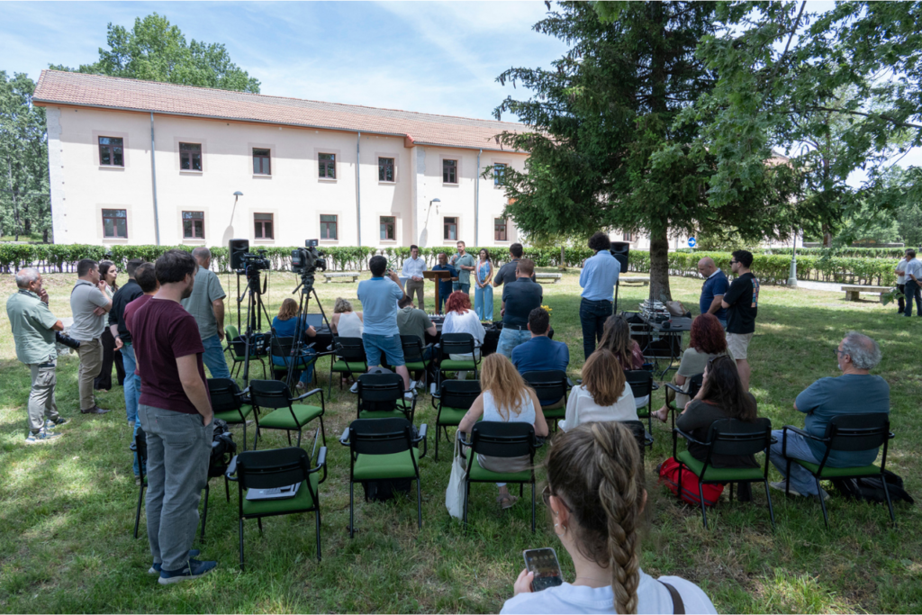 Momento de la rueda de prensa en los jardines, con al hospedería al fondo y la asistencia de periodistas. Interviniendo, el presidente de la diputación, acompañado de los dos vicepresidentes y el alcalde de Piornal